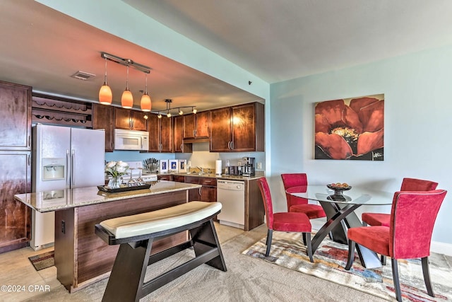 kitchen featuring sink, white appliances, a center island, light stone countertops, and decorative light fixtures