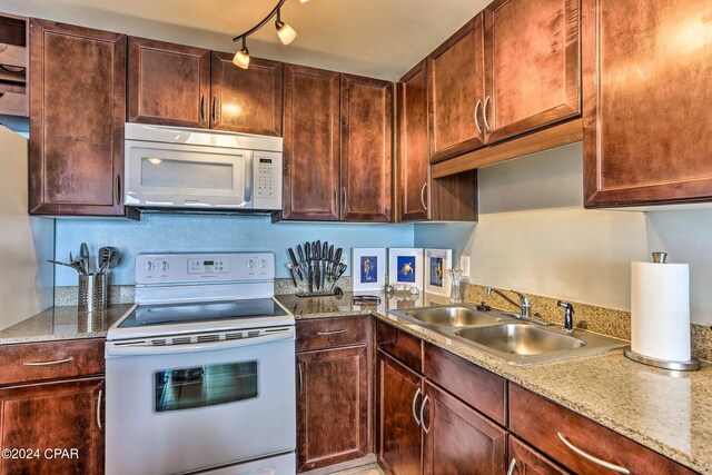 kitchen featuring sink, white appliances, and light stone countertops