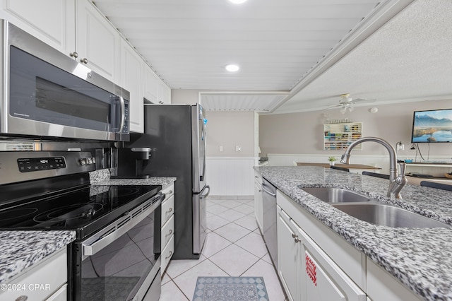 kitchen with appliances with stainless steel finishes, white cabinetry, light stone countertops, ceiling fan, and sink