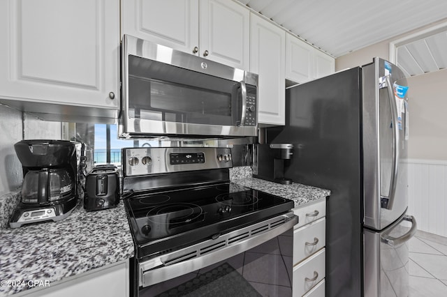 kitchen featuring light stone counters, white cabinets, stainless steel appliances, and light tile patterned floors