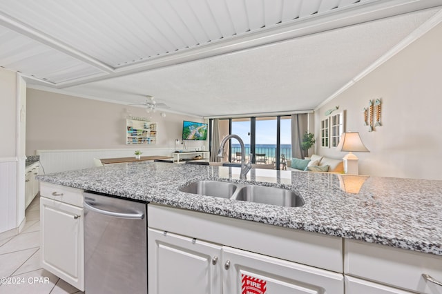 kitchen featuring white cabinets, light stone countertops, ceiling fan, ornamental molding, and sink