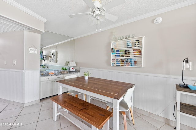 dining area featuring a textured ceiling, ornamental molding, light tile patterned flooring, and ceiling fan