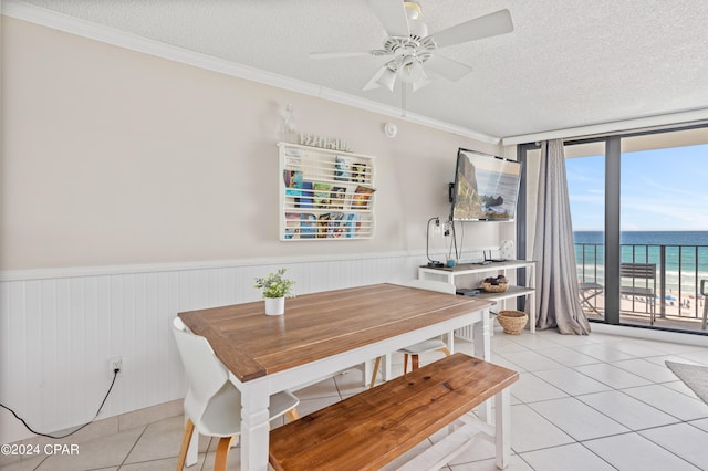 dining space with ceiling fan, a textured ceiling, crown molding, and light tile patterned floors