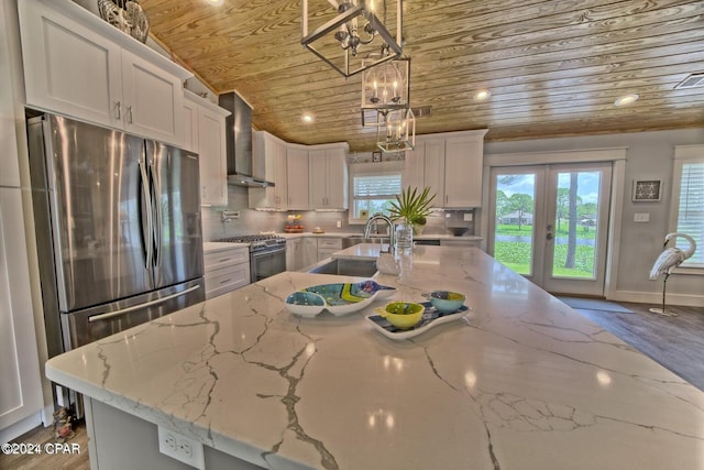 kitchen featuring wooden ceiling, wall chimney range hood, white cabinetry, and stainless steel appliances