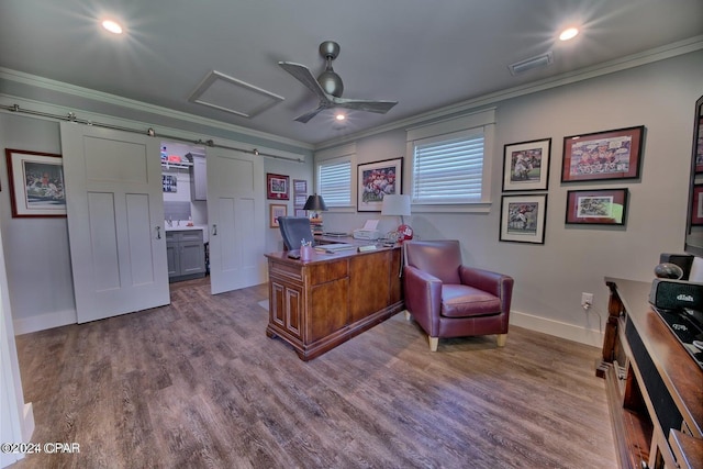 office space featuring a barn door, wood finished floors, visible vents, baseboards, and ornamental molding