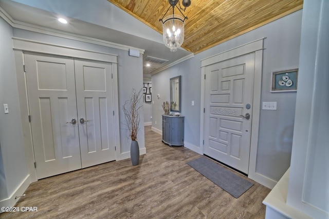 foyer entrance featuring crown molding, visible vents, wood ceiling, wood finished floors, and baseboards