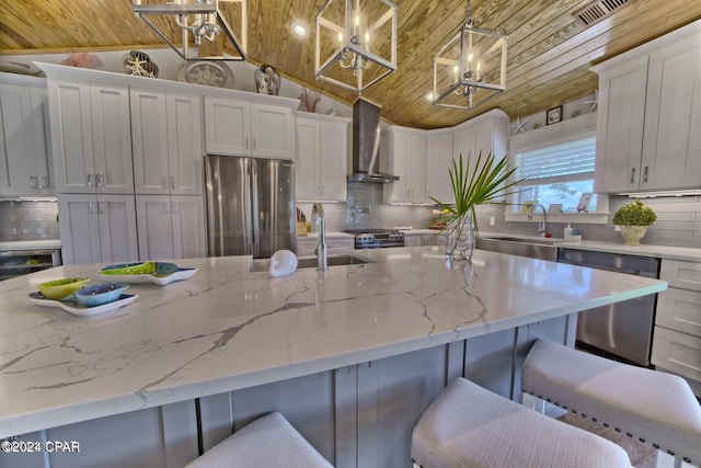 kitchen with wall chimney range hood, wood ceiling, appliances with stainless steel finishes, and a sink