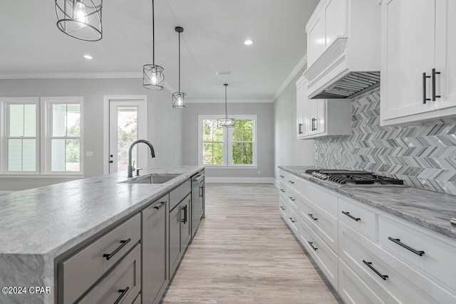 kitchen featuring premium range hood, sink, tasteful backsplash, a kitchen island with sink, and white cabinets