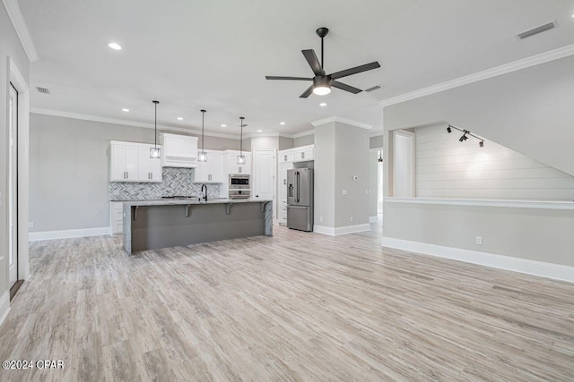 kitchen featuring a breakfast bar, white cabinetry, appliances with stainless steel finishes, pendant lighting, and a kitchen island with sink