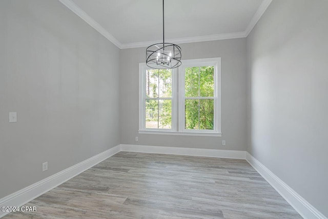 unfurnished room with an inviting chandelier, crown molding, and light hardwood / wood-style flooring