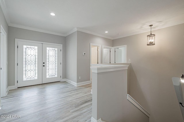 foyer entrance featuring ornamental molding, french doors, and light wood-type flooring