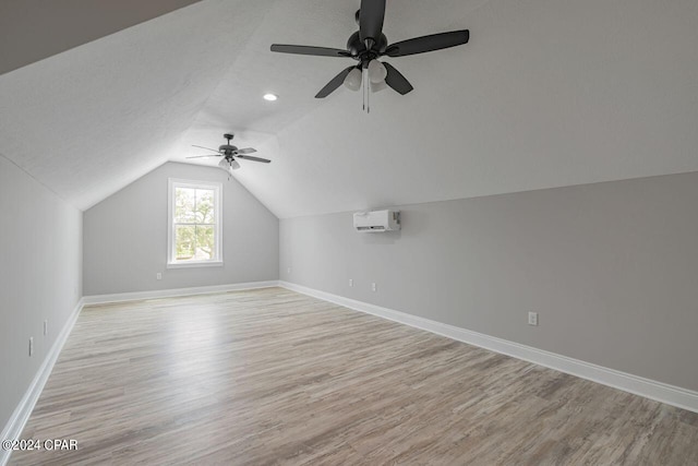 bonus room featuring ceiling fan, lofted ceiling, a wall mounted AC, and light hardwood / wood-style floors