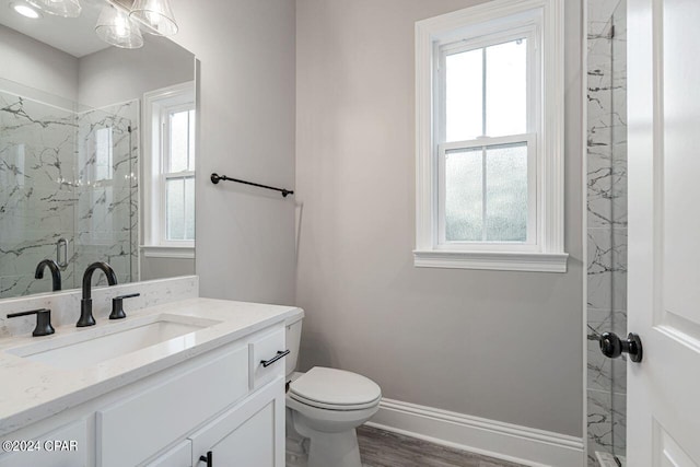 bathroom featuring vanity, wood-type flooring, toilet, and tiled shower