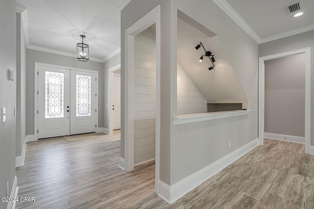 foyer entrance with crown molding, light hardwood / wood-style floors, and french doors