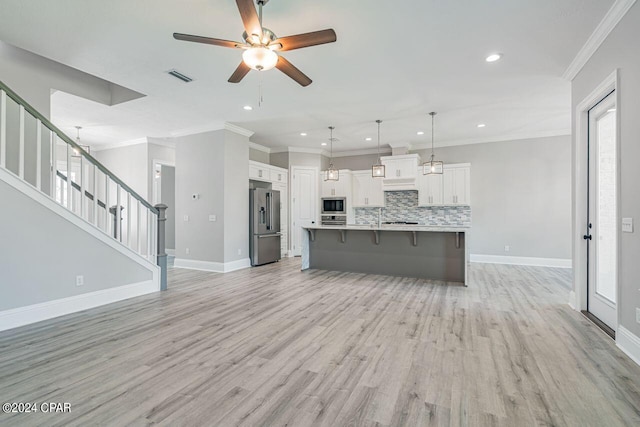 kitchen with white cabinetry, ceiling fan, decorative backsplash, an island with sink, and appliances with stainless steel finishes