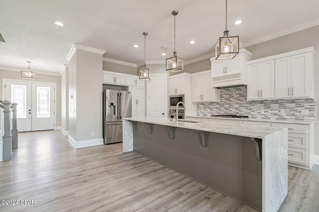 kitchen with decorative backsplash, white cabinetry, appliances with stainless steel finishes, and light wood-type flooring