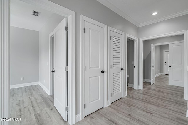 hall with ornamental molding and light hardwood / wood-style flooring