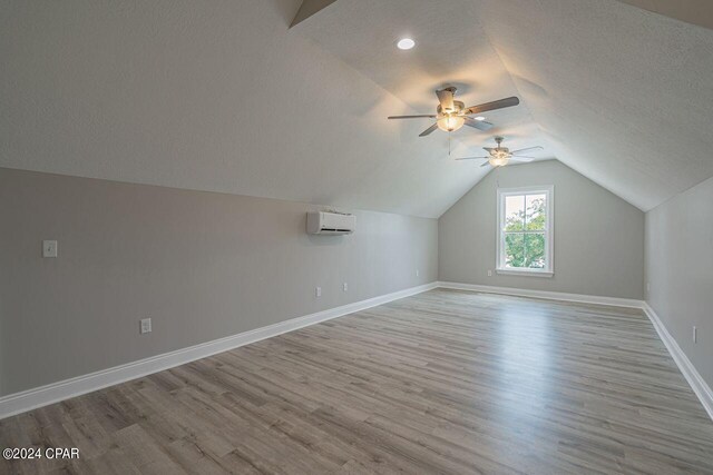 bonus room featuring hardwood / wood-style flooring, ceiling fan, an AC wall unit, a textured ceiling, and lofted ceiling