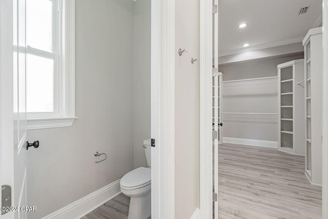 bathroom featuring ornamental molding, wood-type flooring, and toilet