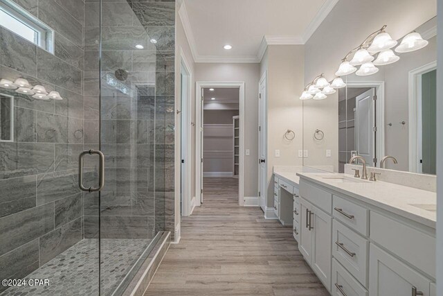 bathroom featuring hardwood / wood-style flooring, a shower with door, crown molding, and dual bowl vanity