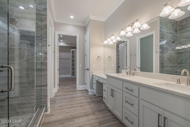 bathroom with hardwood / wood-style flooring, dual vanity, ornamental molding, and an enclosed shower