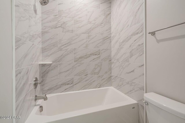 bathroom featuring tiled shower / bath and toilet