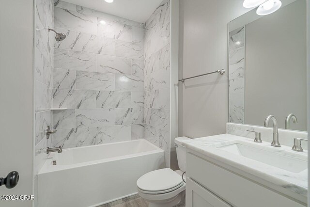 full bathroom featuring vanity, toilet, tiled shower / bath, and hardwood / wood-style floors