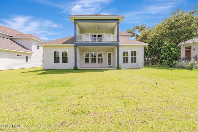 rear view of house with a balcony, ceiling fan, and a lawn