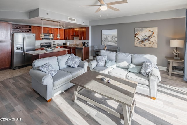 living room featuring sink, ceiling fan, and light wood-type flooring