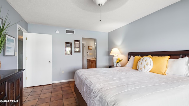 bedroom featuring dark tile patterned flooring, a textured ceiling, ceiling fan, and ensuite bathroom