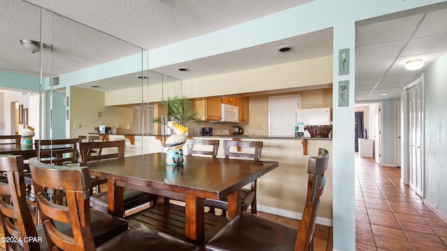 tiled dining room featuring a textured ceiling and a paneled ceiling