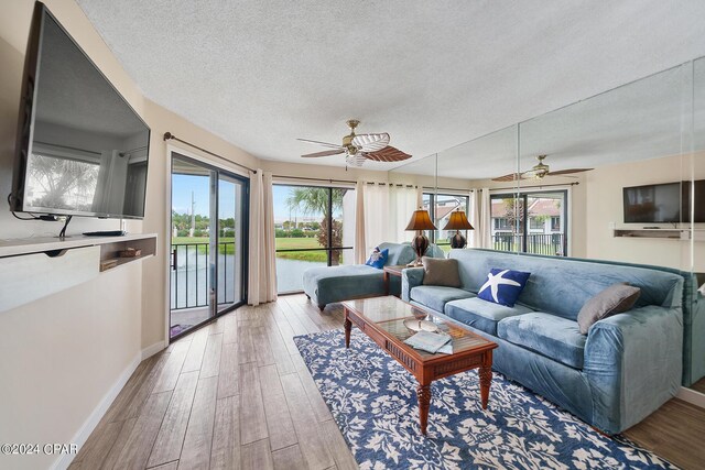 living room featuring light hardwood / wood-style floors, a textured ceiling, and ceiling fan