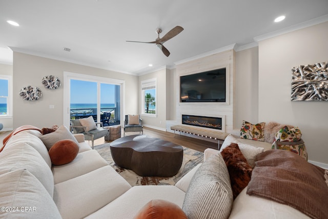 living room featuring ceiling fan, a fireplace, crown molding, and hardwood / wood-style floors