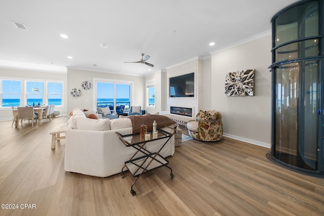 living room featuring ceiling fan, hardwood / wood-style flooring, a healthy amount of sunlight, and a large fireplace