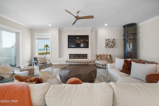 living room featuring a fireplace, wood-type flooring, crown molding, and ceiling fan