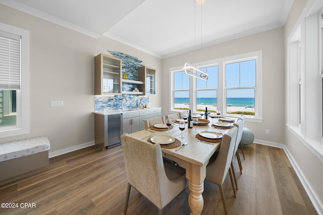 dining area with sink, a water view, ornamental molding, and hardwood / wood-style floors