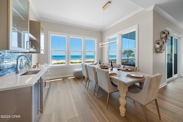 dining area featuring sink, light hardwood / wood-style flooring, a water view, and crown molding