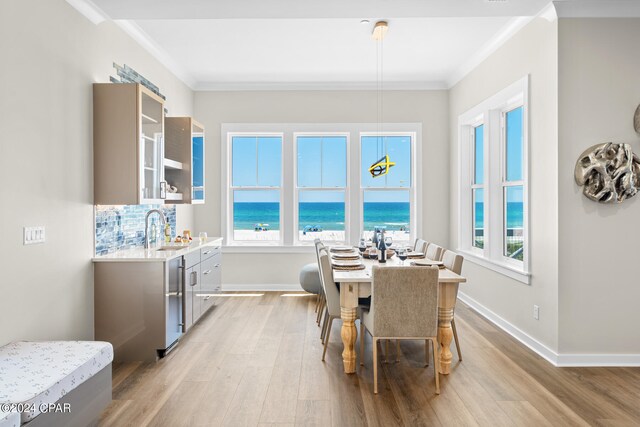 dining room with ornamental molding, sink, a water view, and hardwood / wood-style flooring