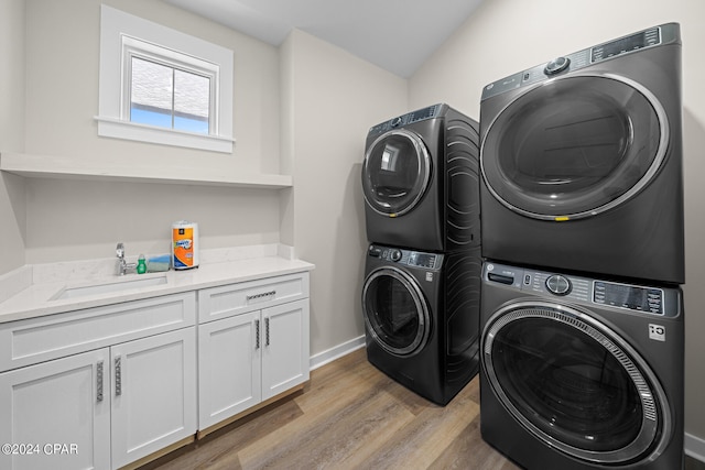 clothes washing area with hardwood / wood-style flooring, stacked washer / drying machine, sink, and cabinets