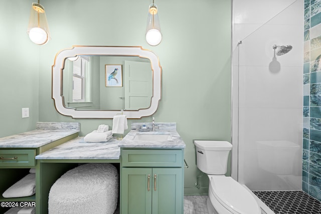 bathroom with vanity, tiled shower, and toilet