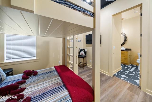 bedroom featuring ensuite bathroom and wood-type flooring