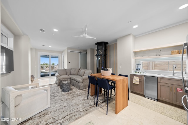 tiled living room featuring a barn door, sink, and ceiling fan