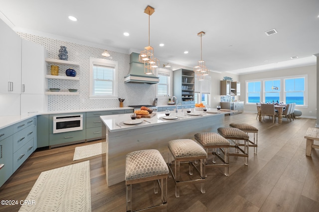 kitchen featuring a center island, dark hardwood / wood-style flooring, hanging light fixtures, custom exhaust hood, and wall oven