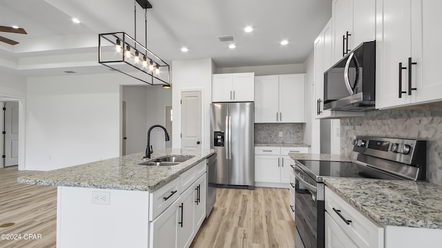 kitchen featuring appliances with stainless steel finishes, sink, a center island with sink, light hardwood / wood-style flooring, and white cabinets