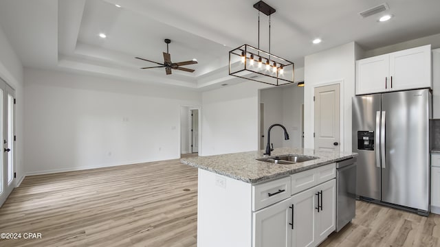 kitchen with white cabinets, sink, light stone countertops, an island with sink, and stainless steel appliances