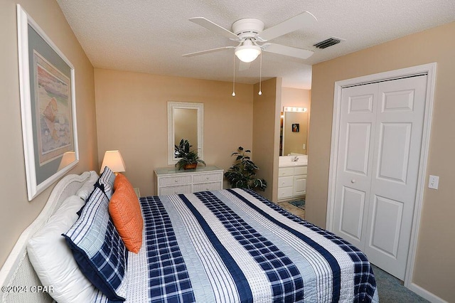 carpeted bedroom with ceiling fan, a closet, ensuite bathroom, and a textured ceiling