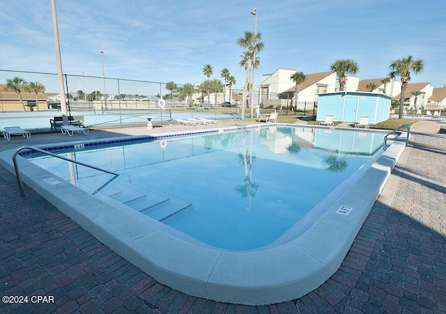 view of swimming pool featuring tennis court