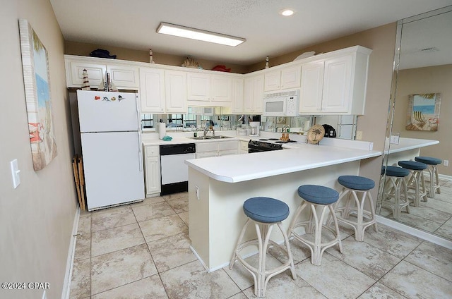 kitchen featuring white cabinetry, white appliances, kitchen peninsula, and a breakfast bar area