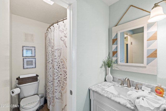 bathroom featuring a textured ceiling, vanity, and toilet