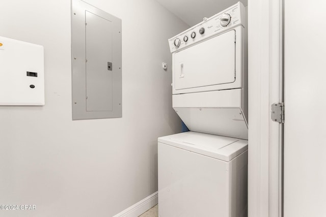 laundry room featuring electric panel, baseboards, laundry area, and stacked washer / dryer